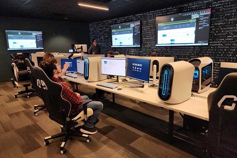 Students in a computer classroom talking about something being presented on the front screen