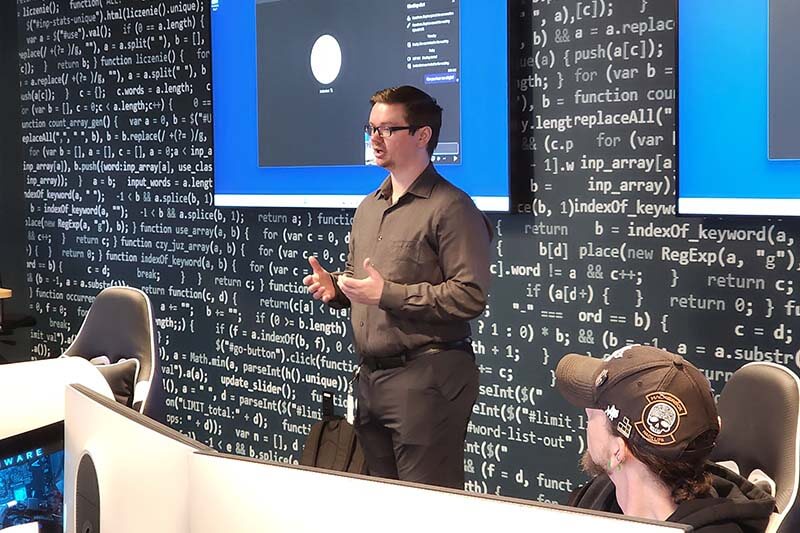 A male teacher standing and giving a lecture in a computer classroom