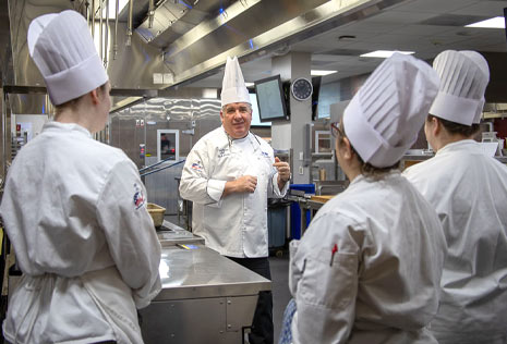 Chef with students in white chef's hats and smocks