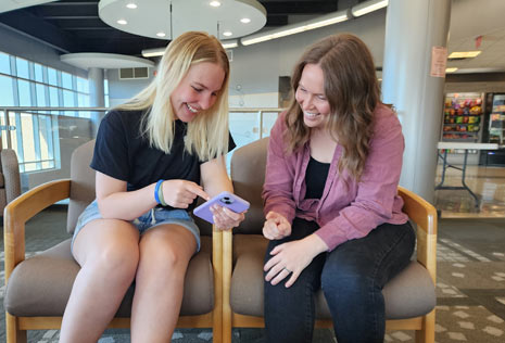 Two college women looking at app on phone