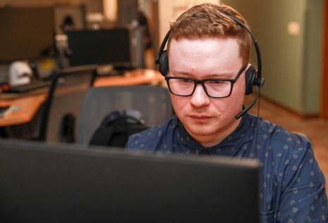 Man with headset on behind a computer