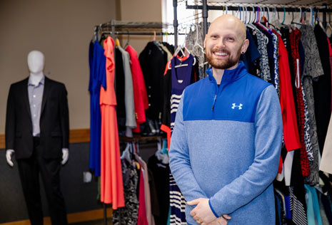 Man in blue pullover shirt standing in career closet at a college