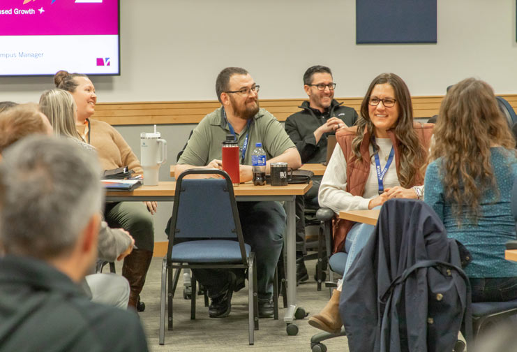Male and female participants sitting at tables and laughing at CVTC's Learn Grow Lead event.